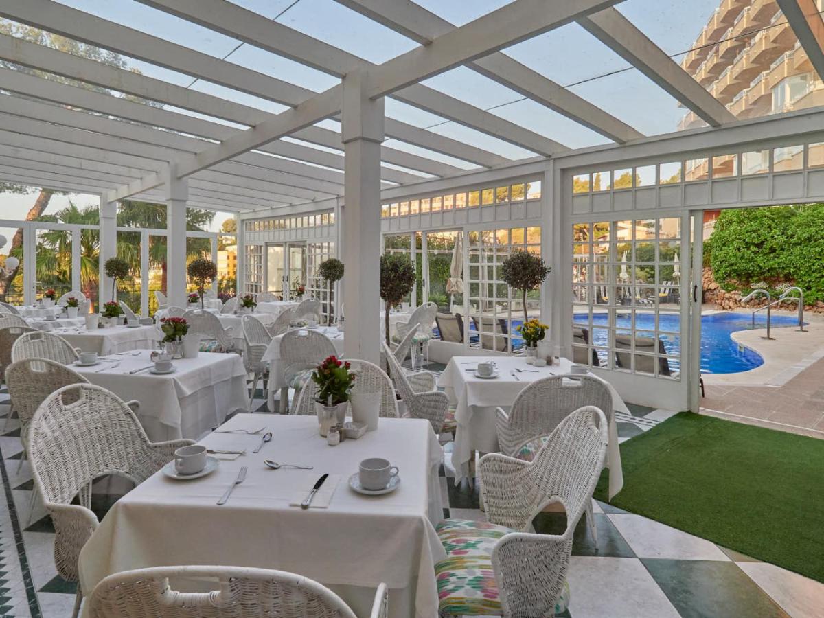 un restaurante con mesas y sillas blancas y una piscina en Hotel Bon Sol Resort & Spa, en Illetas