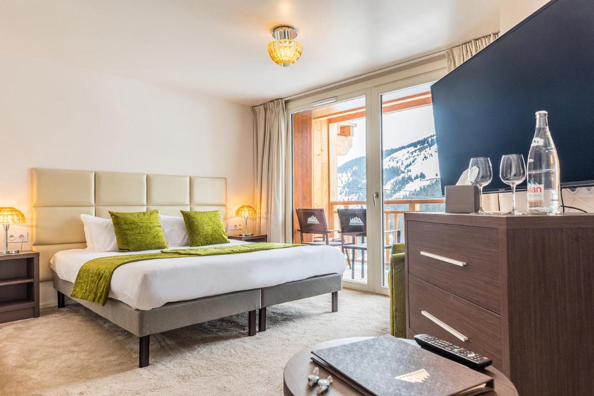 une chambre avec un lit et une grande fenêtre dans l'établissement Madame Vacances Hôtel & Spa Le Mottaret, à Méribel