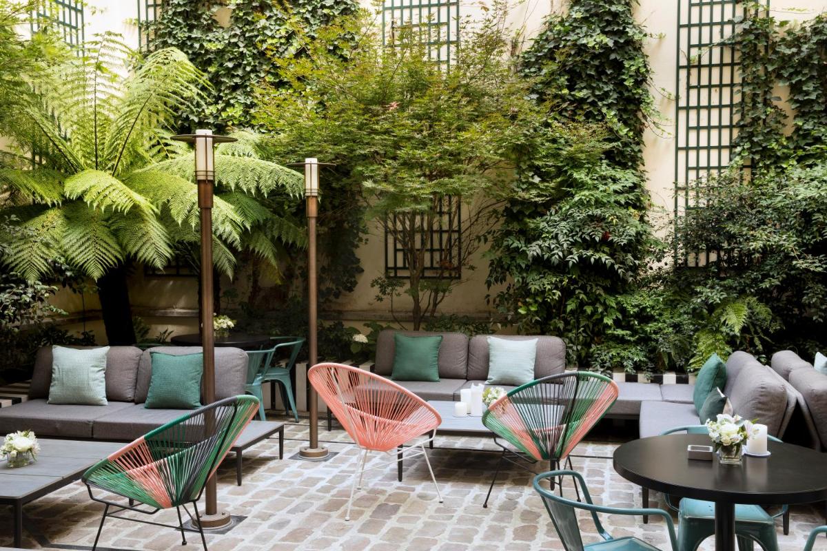 un patio avec tables, chaises et plantes dans l'établissement Hôtel Saint-Marc, à Paris