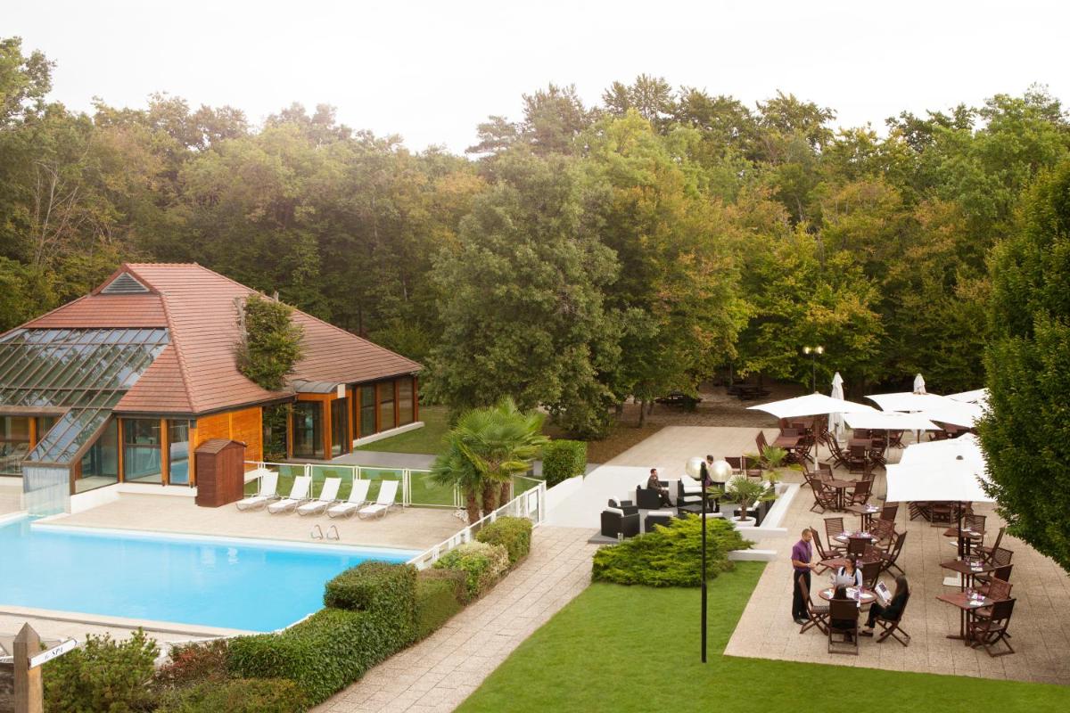 vue aérienne d'un complexe hôtelier avec piscine, tables et chaises dans l'établissement Novotel Fontainebleau Ury, à Ury