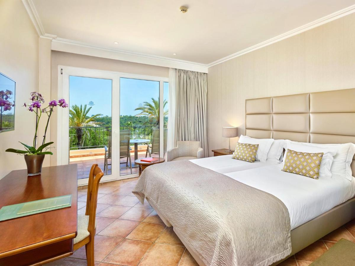 um quarto com uma cama, uma escrivaninha e uma varanda em Ria Park Hotel & Spa no Vale do Lobo