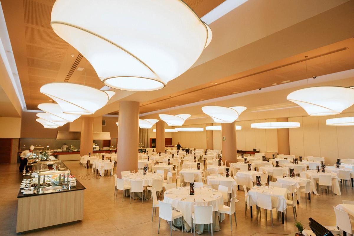 Un gran salón de banquetes con mesas y sillas blancas. en Hotel Deloix 4* Sup, en Benidorm