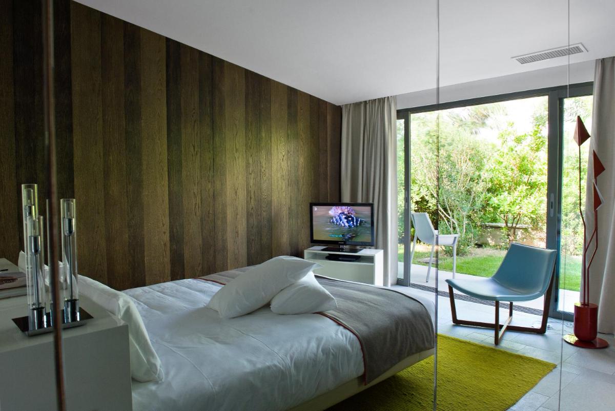 une chambre avec un lit, une télévision et une chaise dans l'établissement Sezz Saint-Tropez, à Saint-Tropez une chambre avec un lit, une télévision et une chaise dans l'établissement Sezz Saint-Tropez, à Saint-Tropez