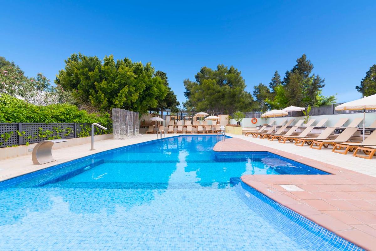 una piscina con tumbonas y una piscina en azuLine Hotel Bergantin, en Bahía de San Antonio