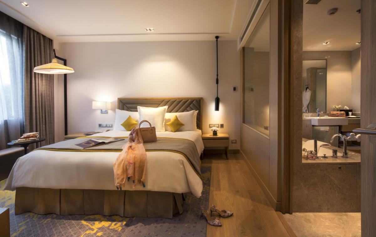 a hotel room with a large bed and a bathroom at Welcomhotel by ITC Hotels, RaceCourse, Coimbatore in Coimbatore