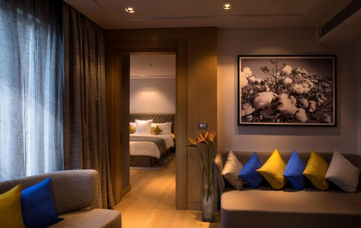 a hotel room with a bed and a couch with pillows at Welcomhotel by ITC Hotels, RaceCourse, Coimbatore in Coimbatore