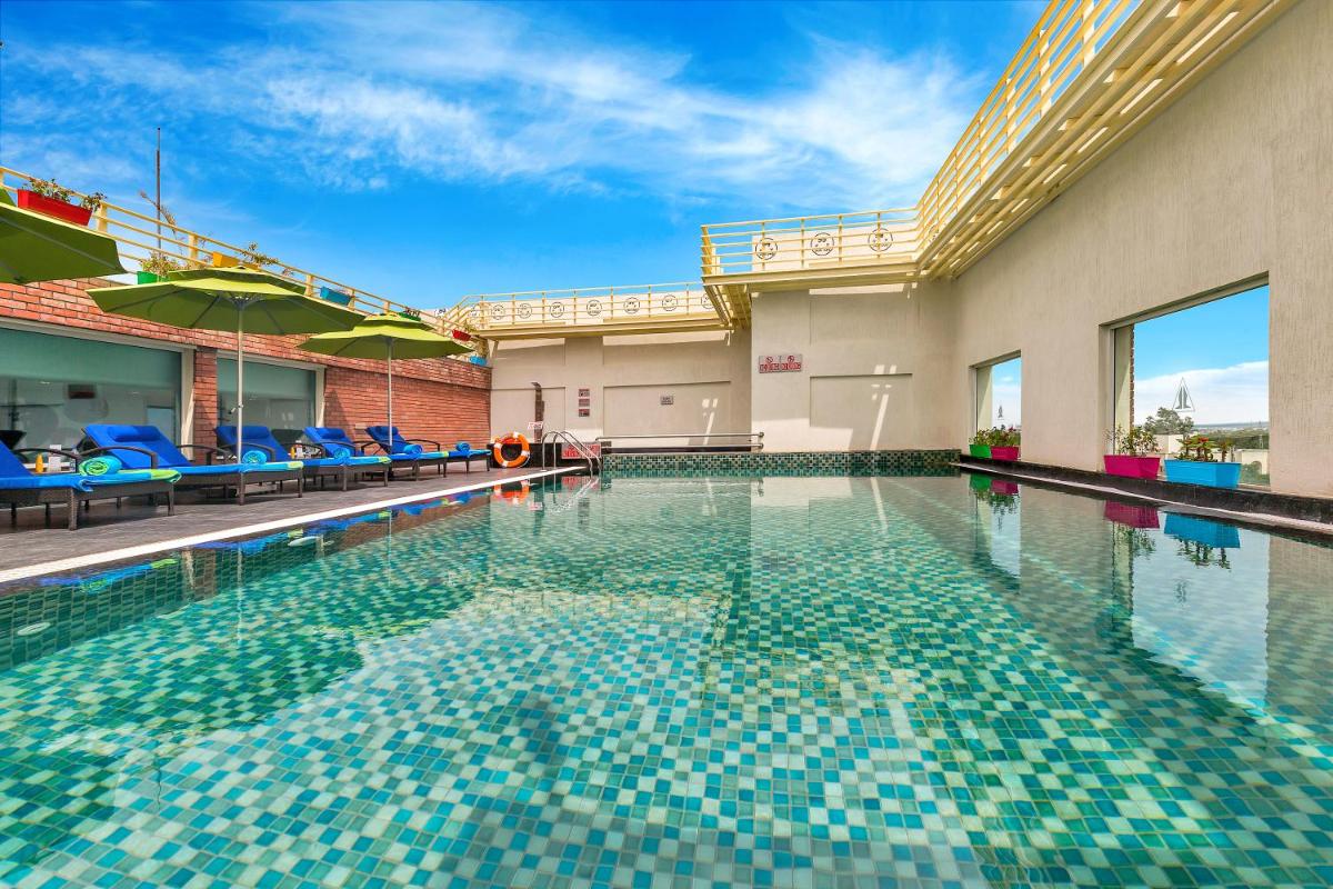 a swimming pool with blue chairs and umbrellas at Welcomhotel by ITC Hotels, RaceCourse, Coimbatore in Coimbatore