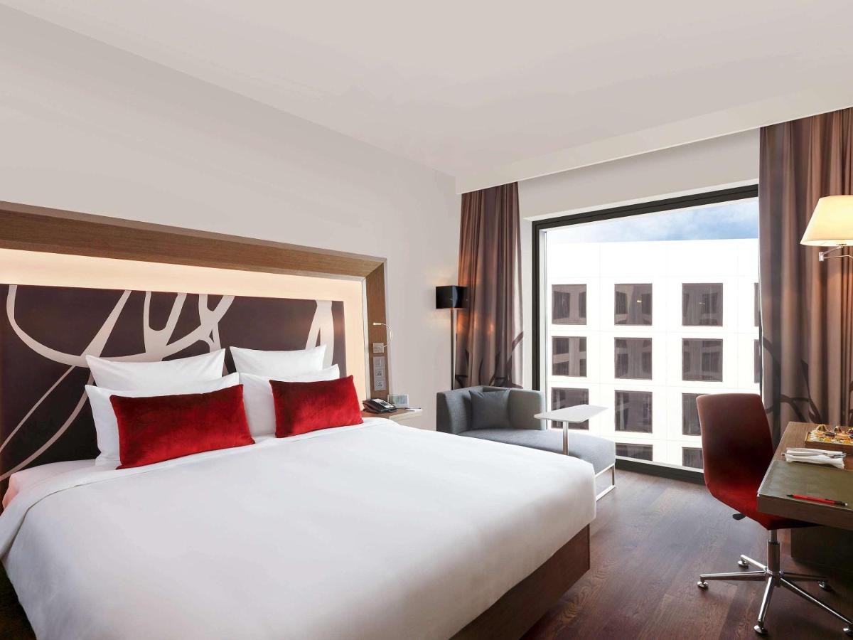 a hotel room with a large bed with red pillows at Novotel New Delhi Aerocity in New Delhi