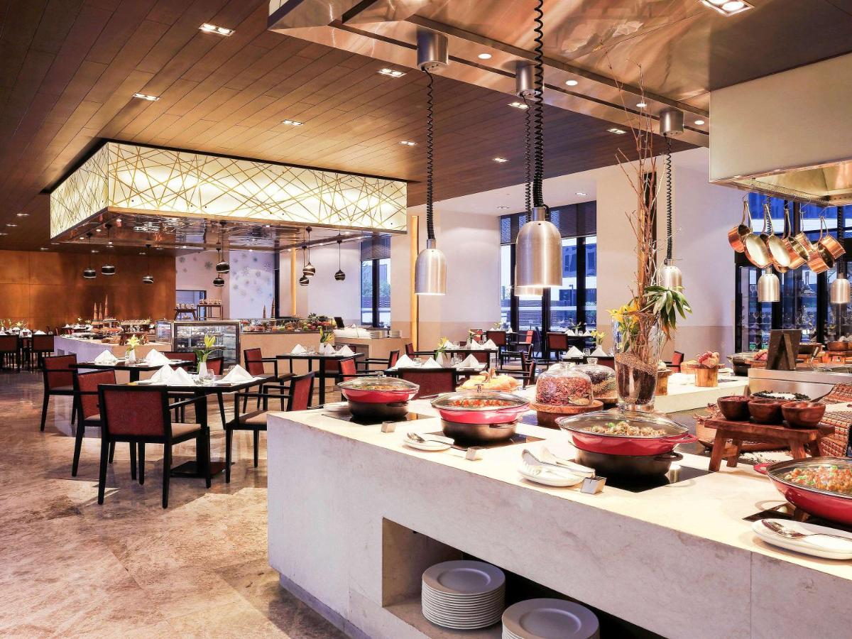 a restaurant with tables and chairs and a buffet at Novotel New Delhi Aerocity in New Delhi