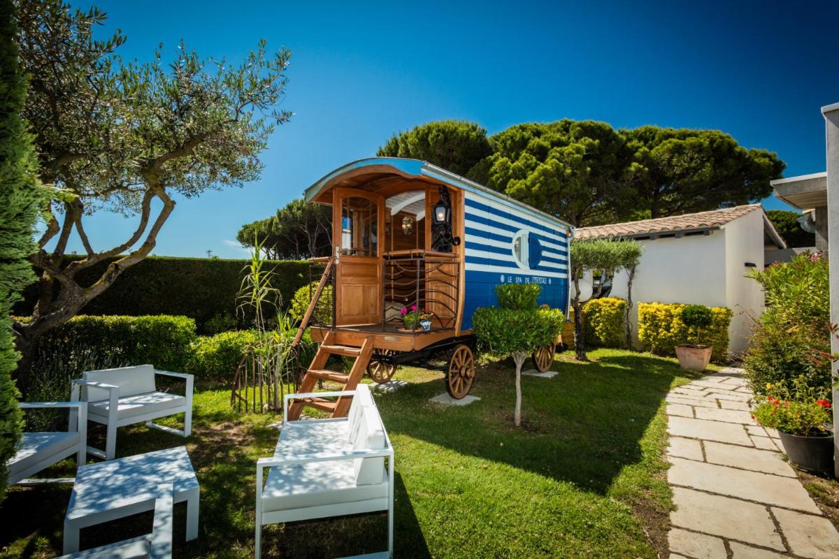 une petite maison dans une cour avec un abri de jardin dans l'établissement Oustau Camarguen Hôtel & Spa, au Grau-du-Roi