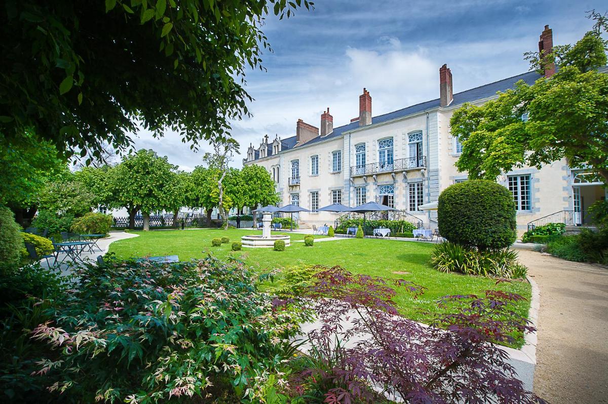 un grand bâtiment blanc avec un jardin devant dans l'établissement Hôtel 4 étoiles - Restaurants & Spa Périer Du Bignon, à Laval
