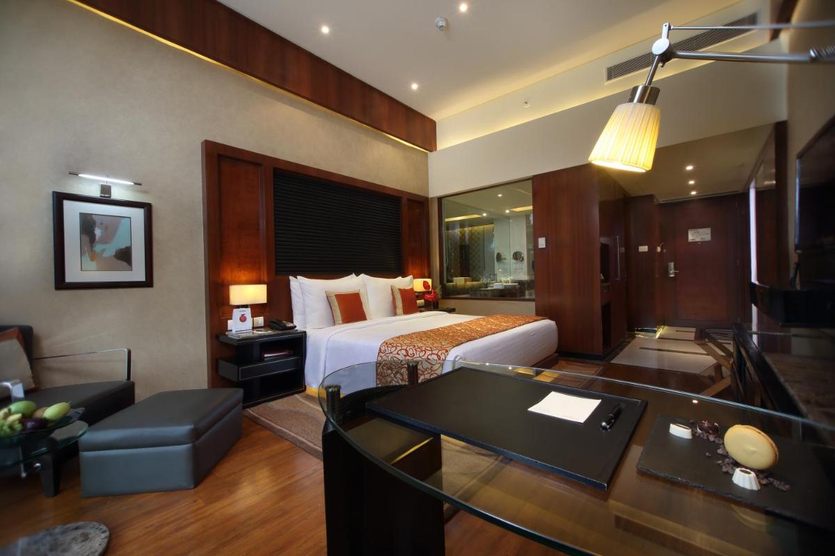 a hotel room with a bed and a desk at Gokulam Grand Hotel & Spa Bangalore in Bengaluru a hotel room with a bed and a desk at Gokulam Grand Hotel & Spa Bangalore in Bengaluru