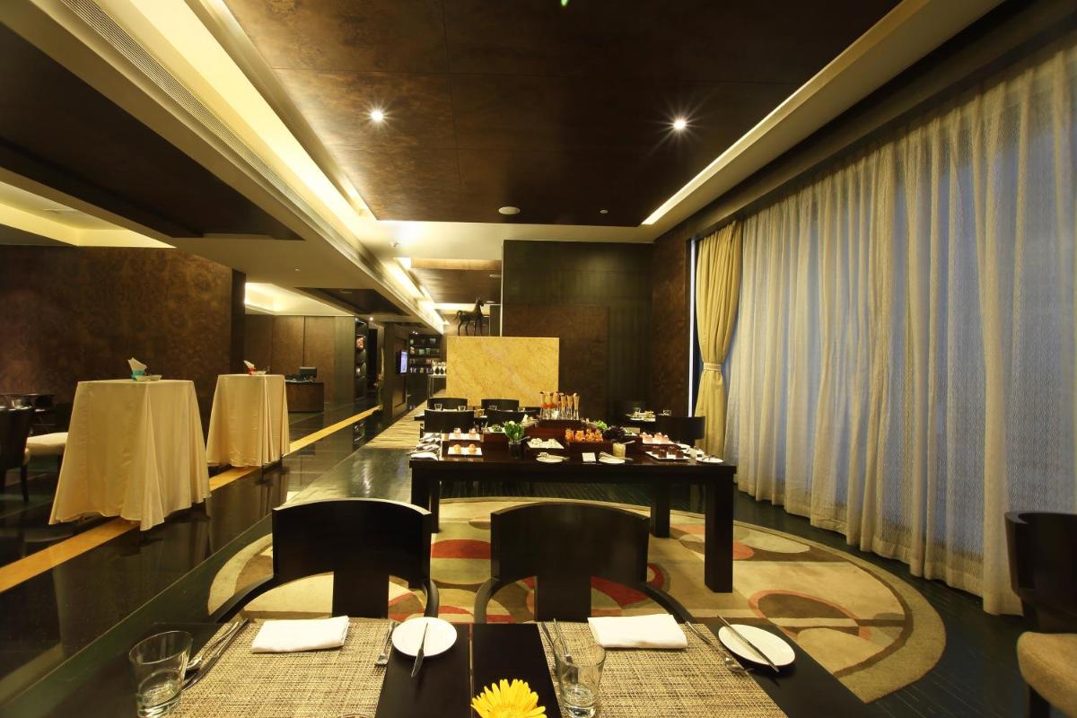 a dining room with a long table and chairs at Gokulam Grand Hotel & Spa Bangalore in Bengaluru a dining room with a long table and chairs at Gokulam Grand Hotel & Spa Bangalore in Bengaluru