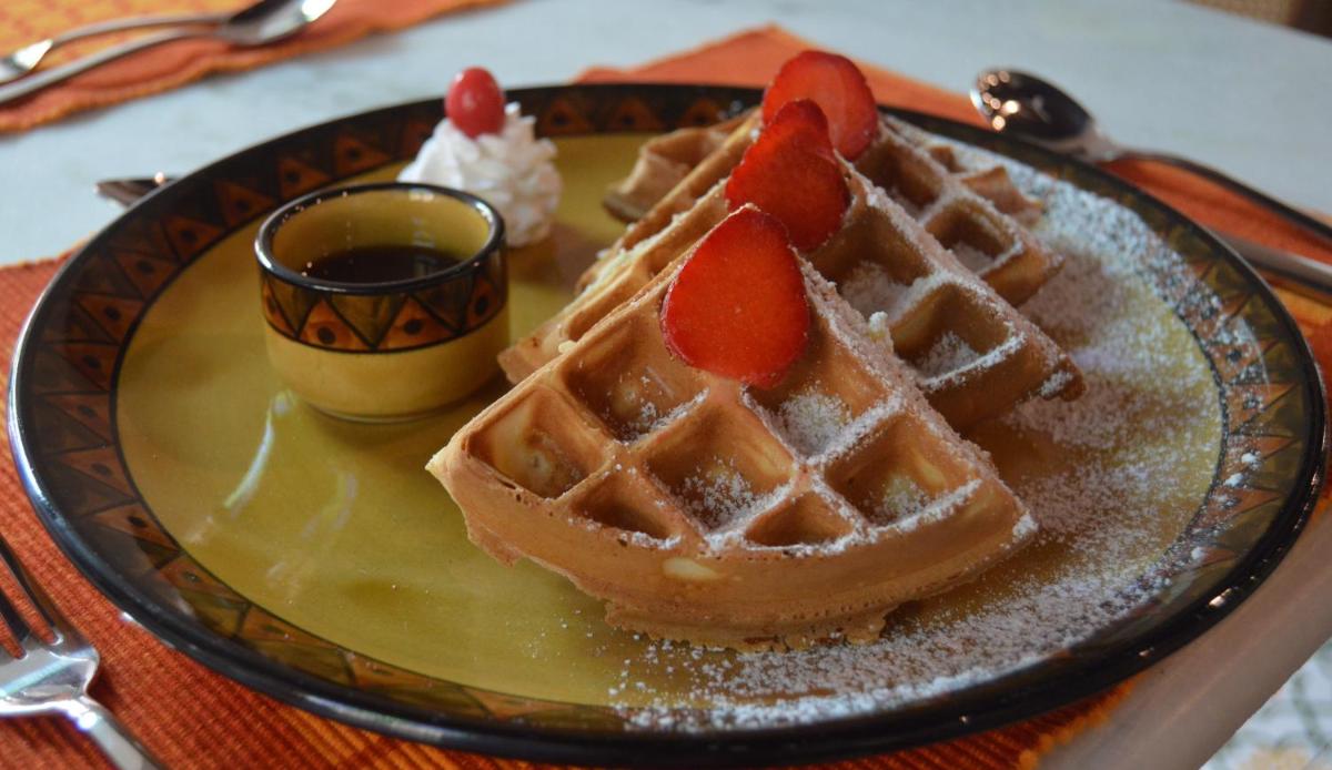a plate with a waffle with strawberries on it at Forte Kochi in Cochin