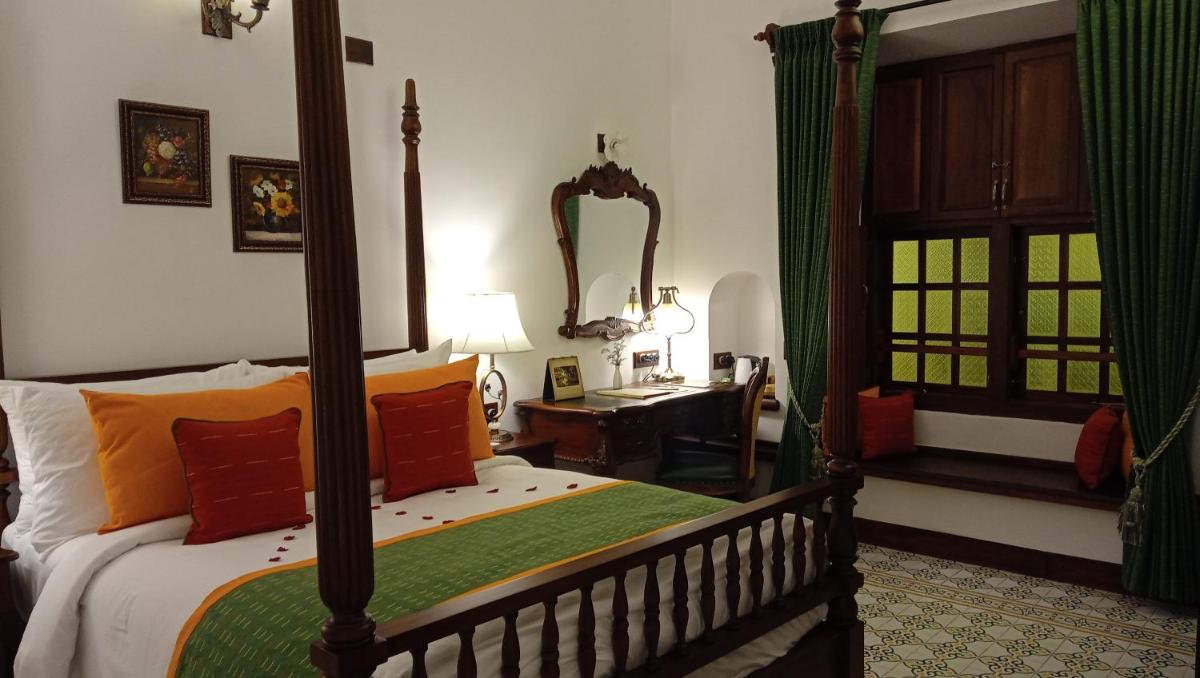 a bedroom with a bed and a desk and a mirror at Forte Kochi in Cochin