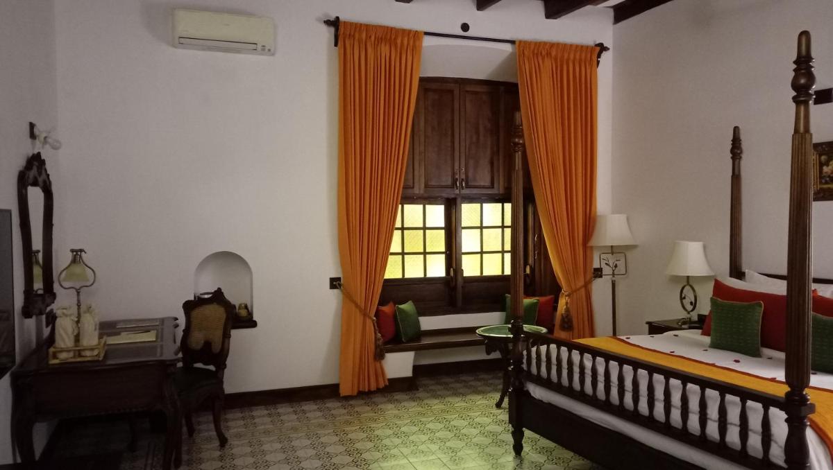 a bedroom with a bed and a window with orange curtains at Forte Kochi in Cochin