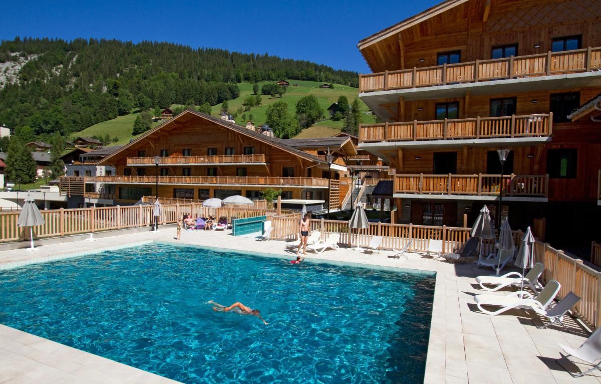 un hôtel avec une piscine devant un immeuble dans l'établissement Hôtel Odalys Le Chamois, à La Clusaz