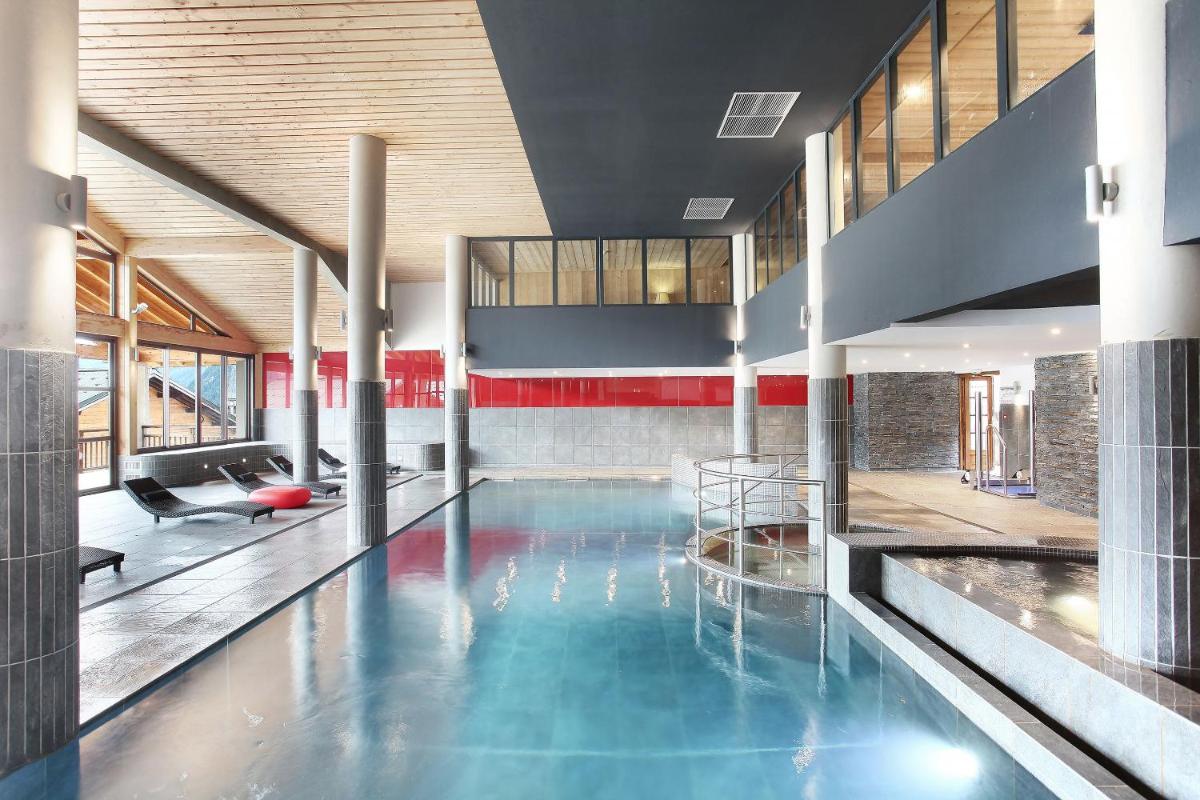 une grande piscine avec de l'eau bleue dans un immeuble dans l'établissement Résidence Odalys Les Fermes de Châtel, à Châtel