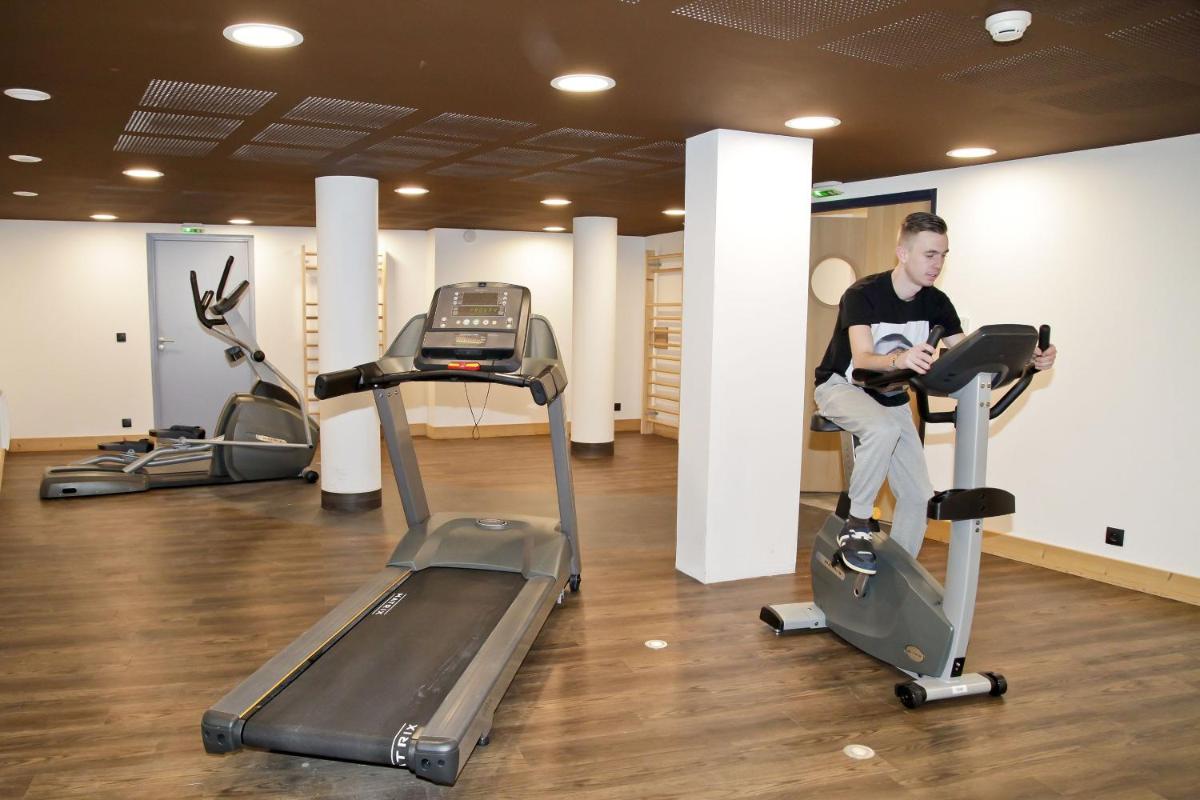 un homme faisant du vélo d'appartement dans une salle de sport dans l'établissement Résidence Odalys Les Fermes de Châtel, à Châtel
