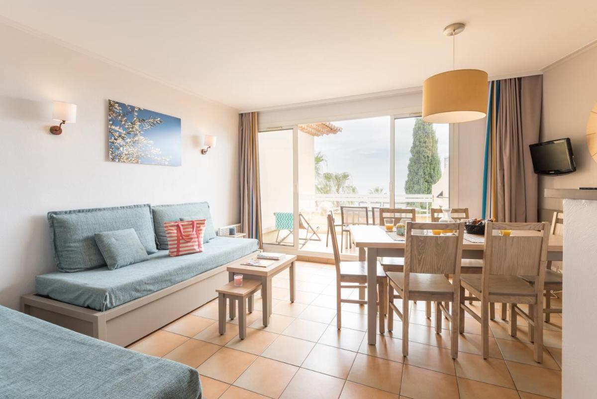 un salon avec un canapé et une salle à manger dans l'établissement Pierre & Vacances Residence Les Rivages des Issambres, aux Issambres