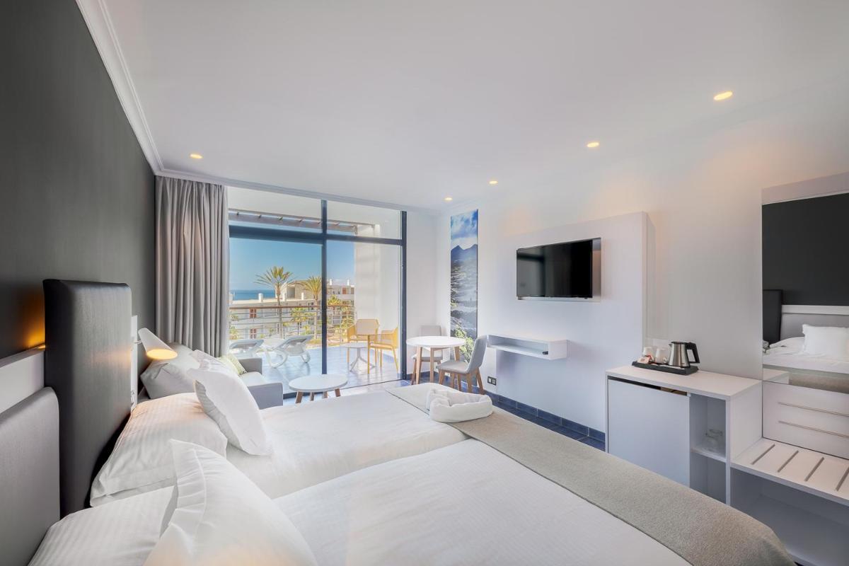 Una habitación de hotel con dos camas y un televisor. en Hotel Mirador Papagayo by LIVVO, en Playa Blanca