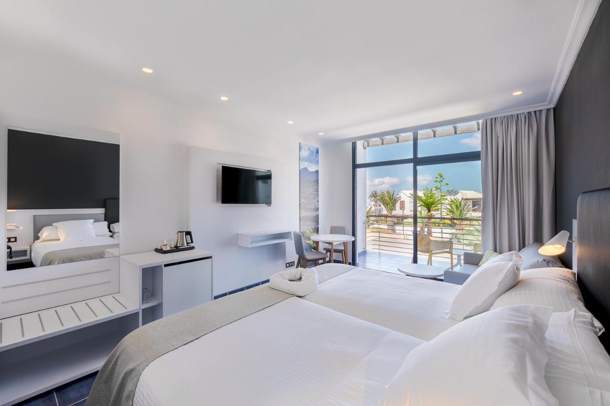 Una habitación de hotel con una cama grande y un balcón. en Hotel Mirador Papagayo by LIVVO, en Playa Blanca