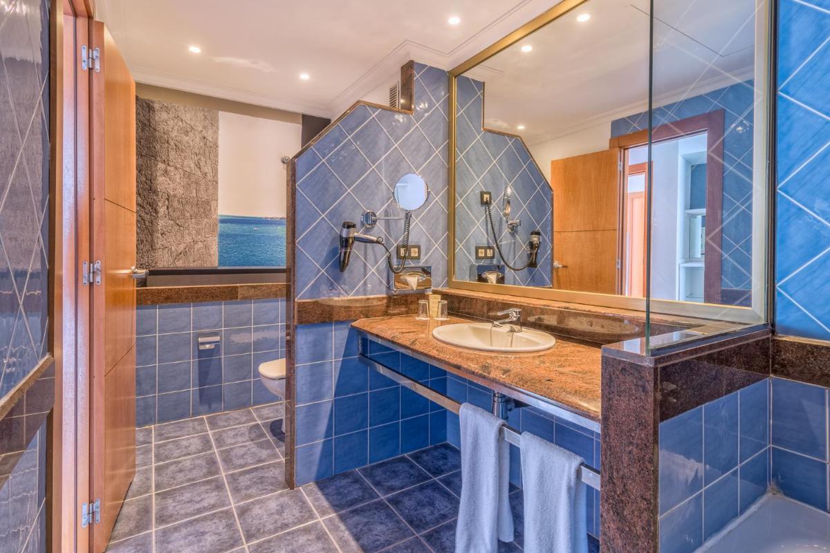 Un baño azul con lavabo y espejo. en Hotel Mirador Papagayo by LIVVO, en Playa Blanca