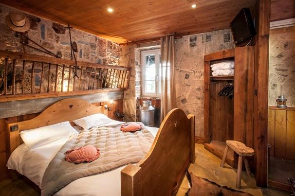 une chambre avec un lit dans une pièce aux murs en bois dans l'établissement Hotel Le Rocher Blanc, à Albaret-Sainte-Marie
