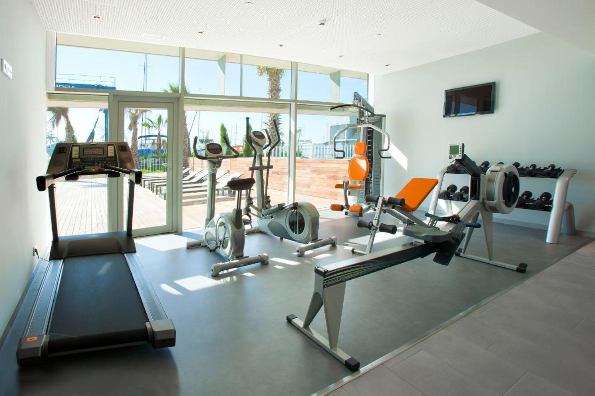 un gimnasio con equipo cardiovascular en una habitación con ventanas en Atenea Port Barcelona Mataró, en Mataró