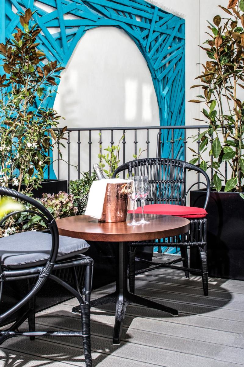 une table et des chaises sur une terrasse aux murs bleus dans l'établissement Hotel Les Bains Paris, à Paris