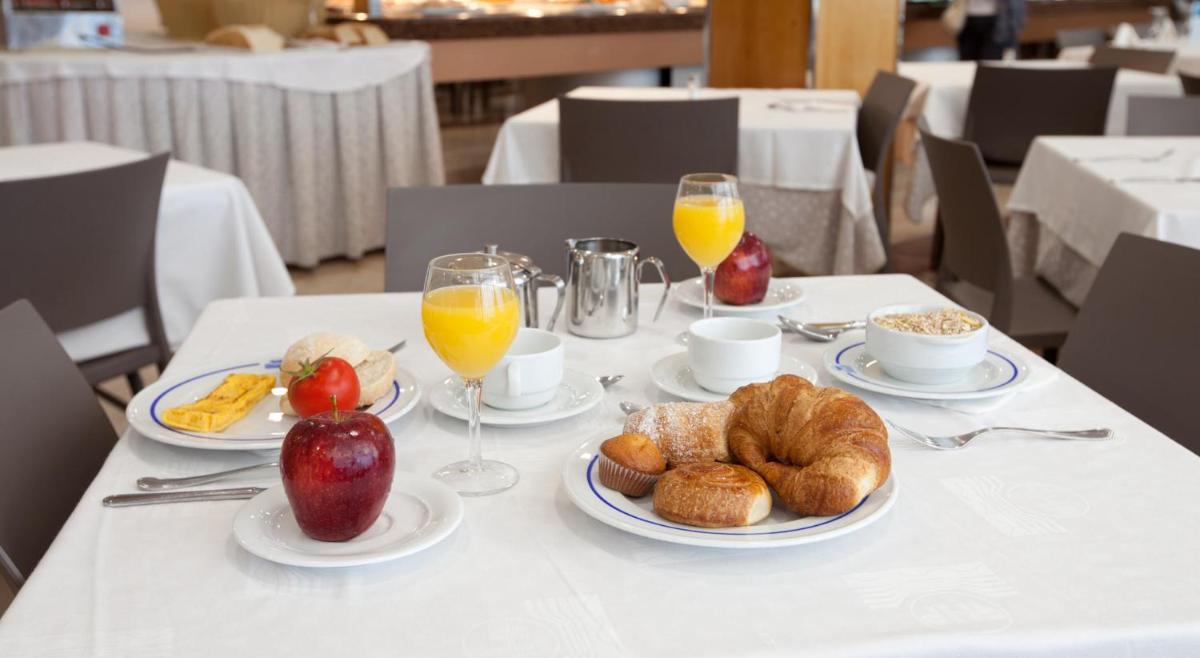 una mesa con platos de comida y vasos de jugo de naranja en Hotel & Spa Peñiscola Palace, en Peñíscola