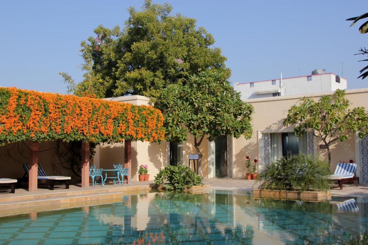 a swimming pool in a courtyard with flowers at Royal Heritage Haveli - By Leisure Hotels in Jaipur