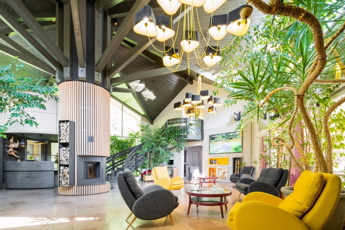 un hall avec des chaises, des tables et des plantes dans l'établissement Le Bois Dormant-Hôtel Restaurant & Spa Logis Hôtel, à Champagnole