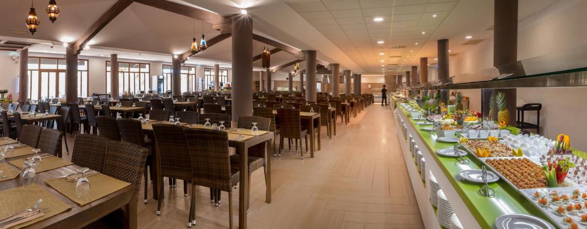 un comedor con mesas, sillas y comida a la vista en Magic Natura Resort, en Benidorm