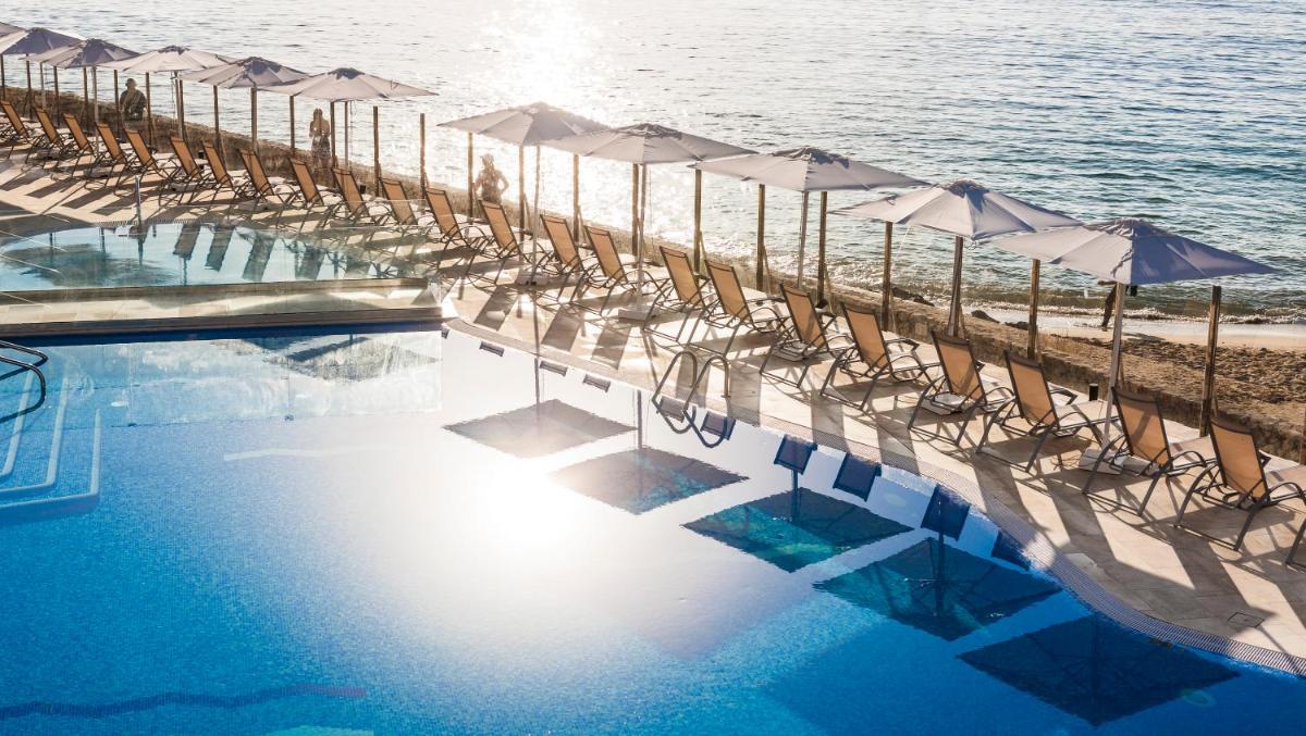 una piscina con sillas y sombrillas junto a la playa en Globales Santa Lucia - Adults Only 18, en Palmanova