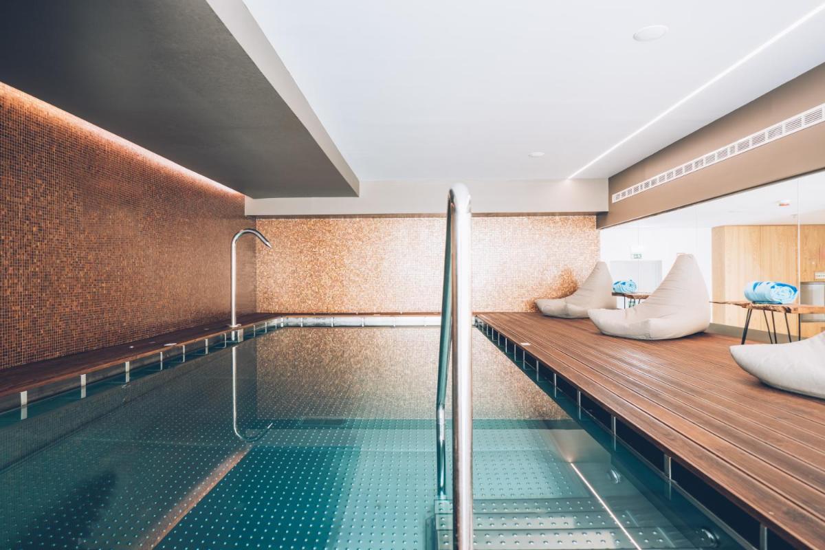 uma piscina com um banco e uma mesa em Iberostar Selection Lisboa em Lisboa