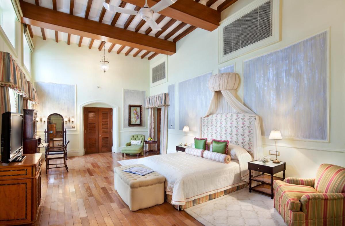 a bedroom with a bed and a couch and a tv at Taj Falaknuma Palace in Hyderabad