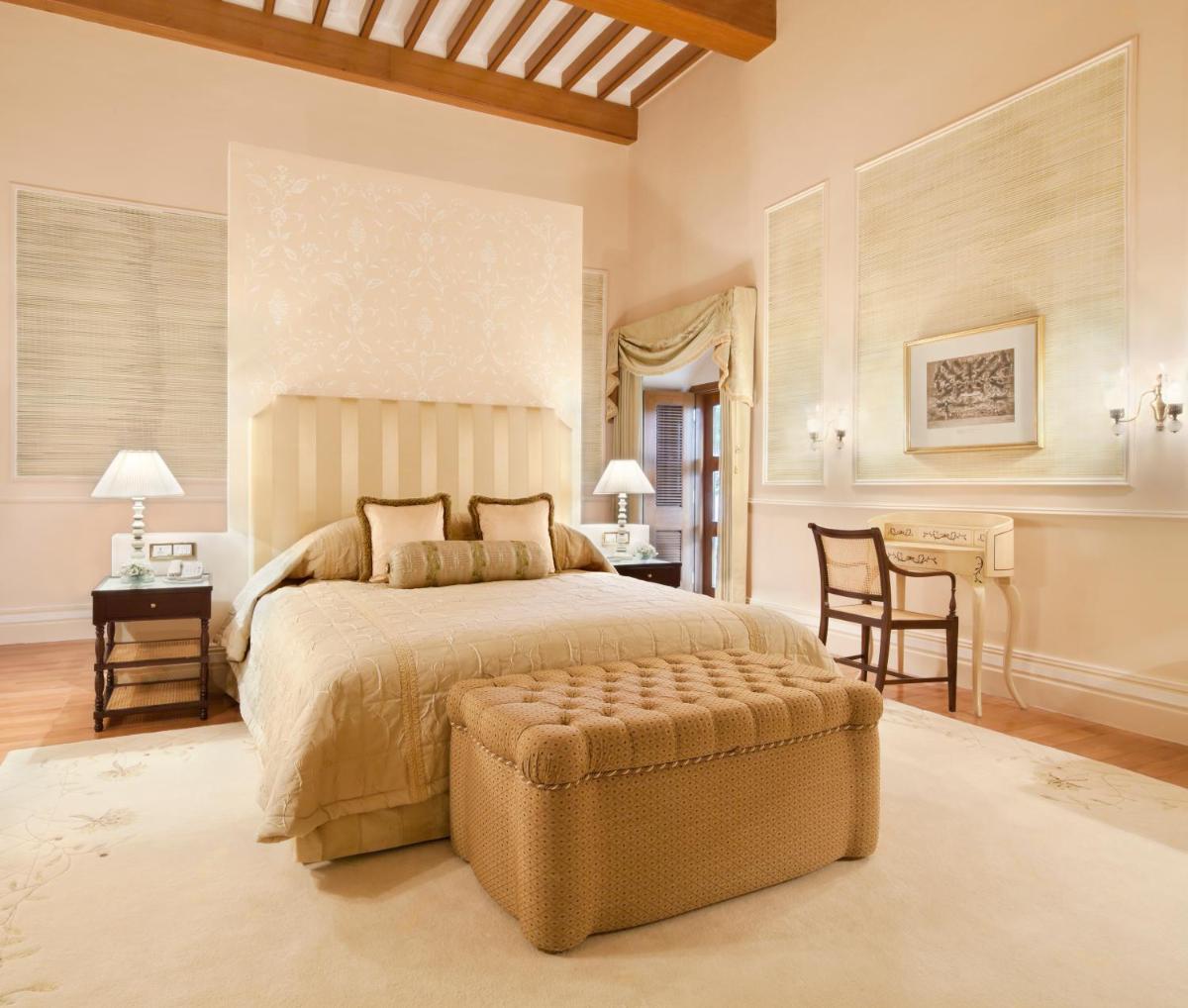 a bedroom with a large bed and a table and chairs at Taj Falaknuma Palace in Hyderabad