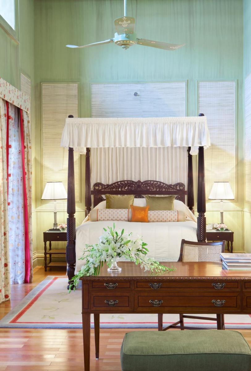 a bedroom with a canopy bed with a wooden desk at Taj Falaknuma Palace in Hyderabad