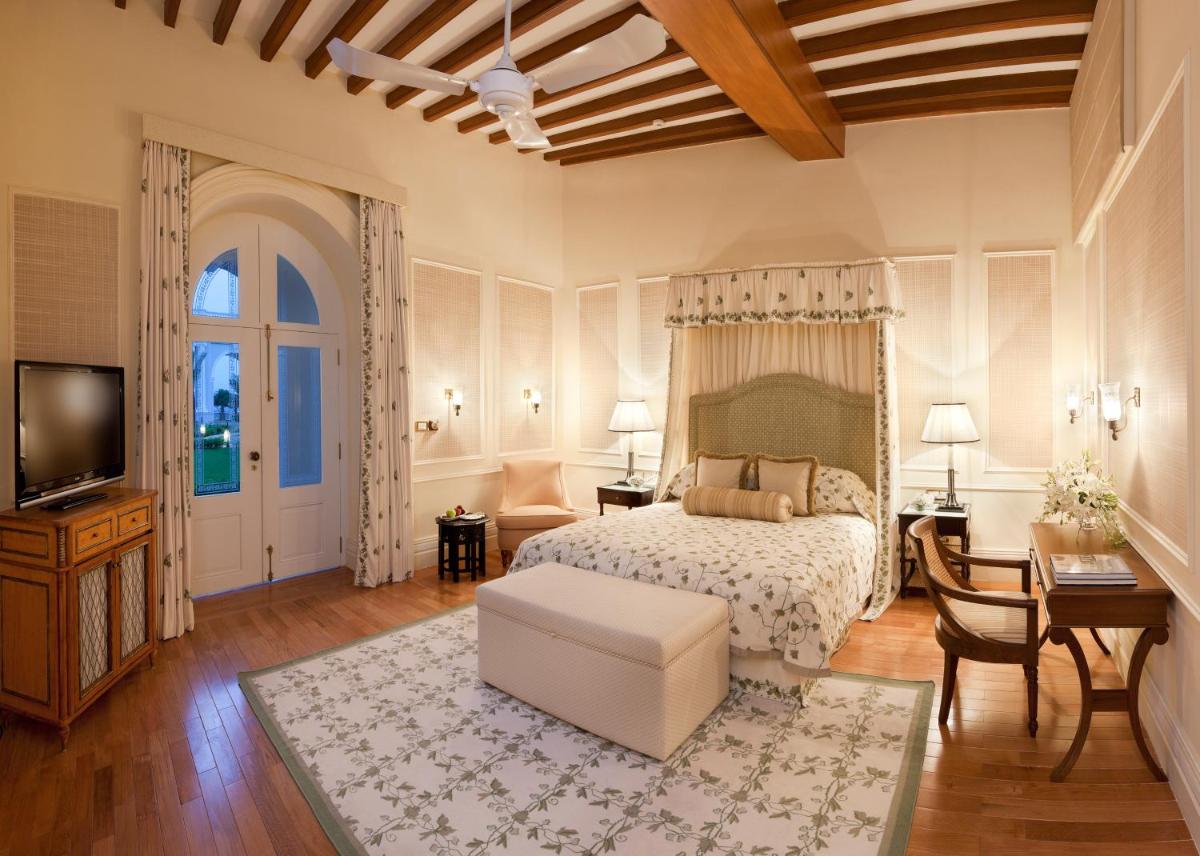 a bedroom with a bed and a table and a tv at Taj Falaknuma Palace in Hyderabad