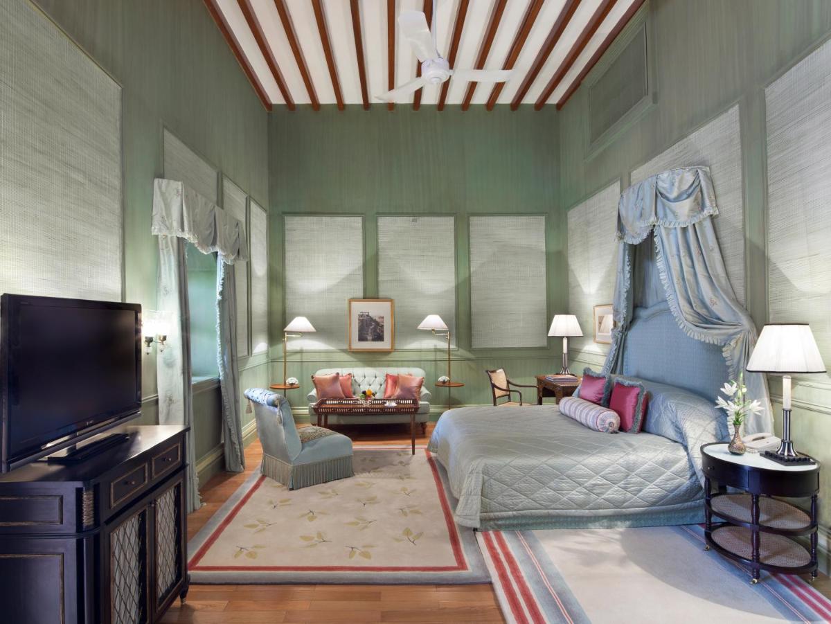 a bedroom with a bed and a couch and a tv at Taj Falaknuma Palace in Hyderabad