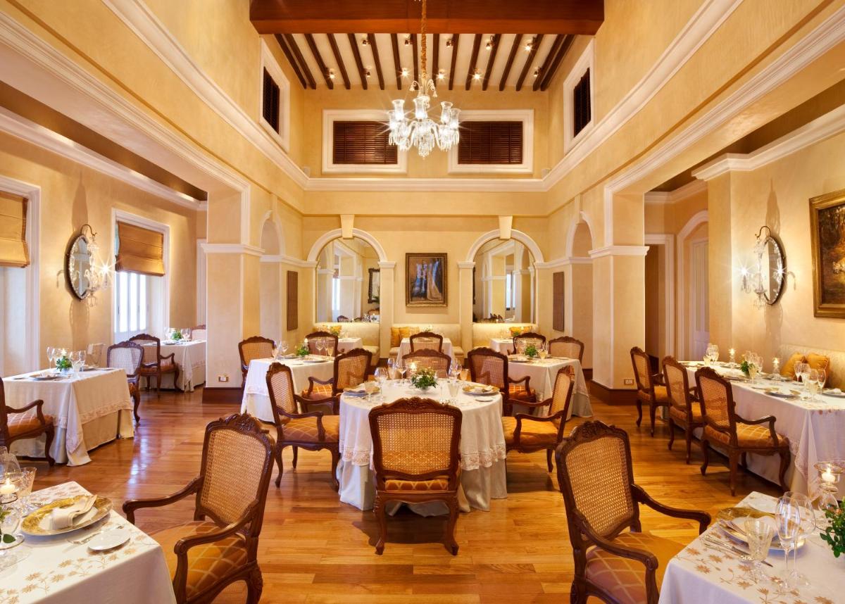 a dining room with tables and chairs and a chandelier at Taj Falaknuma Palace in Hyderabad