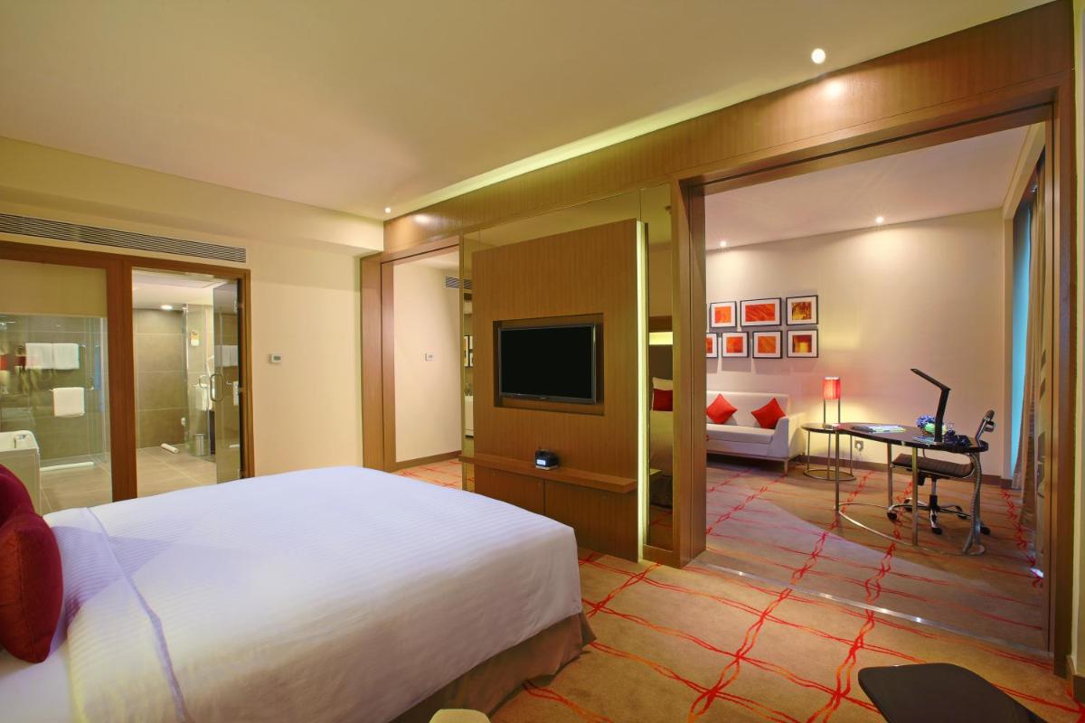 a bedroom with a large bed and a television at Novotel Ahmedabad in Ahmedabad