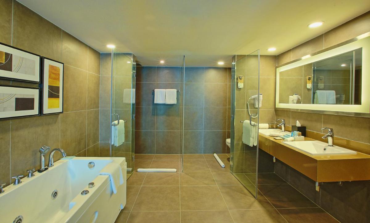 a bathroom with two sinks and a tub and a shower at Novotel Ahmedabad in Ahmedabad