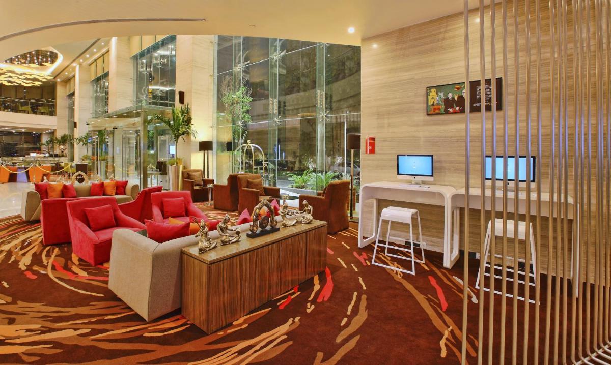 a lobby with a living room with red furniture and a desk at Novotel Ahmedabad in Ahmedabad