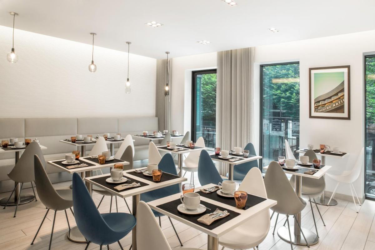 un restaurant avec des tables, des chaises et des fenêtres dans l'établissement BW Premier Collection Le Saint Antoine Hotel et Spa, à Rennes