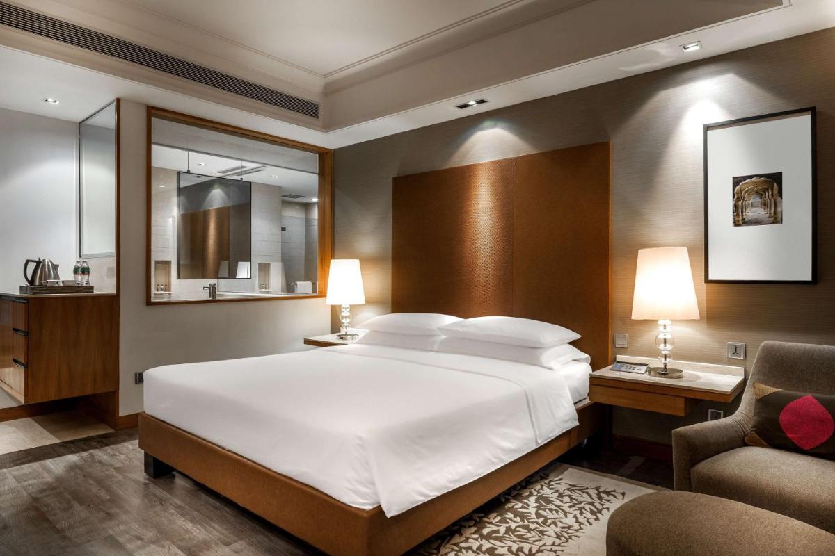 a bedroom with a large white bed and a chair at Hyatt Ahmedabad in Ahmedabad