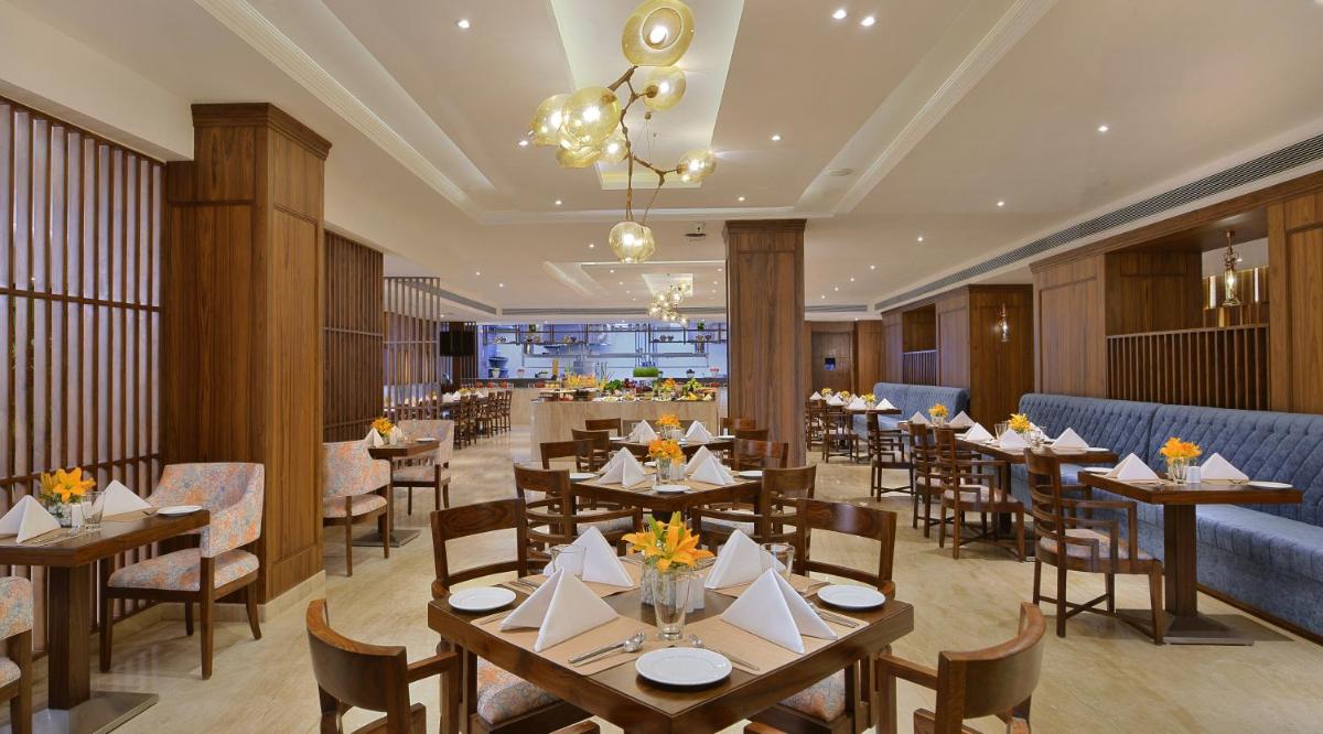 a dining room with tables and chairs and a restaurant at Radisson Chandigarh Zirakpur in Chandīgarh