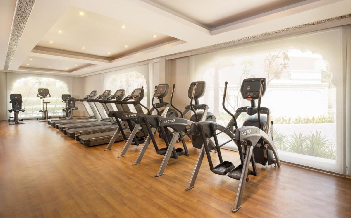 a gym with a row of treadmills and ellipticals at The Leela Palace Jaipur in Jaipur