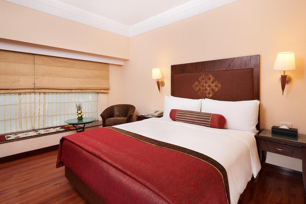 a hotel room with a large bed and a window at The Lalit Ashok in Bengaluru a hotel room with a large bed and a window at The Lalit Ashok in Bengaluru